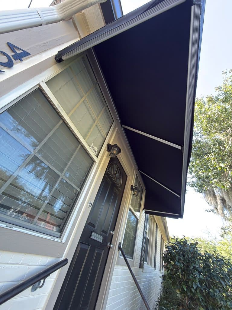 Black retractable awning extended over storefront entrance with glass door and windows below